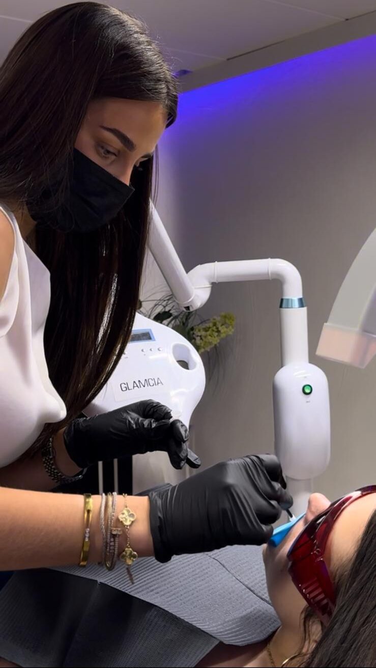 Technicienne esthétique réalisant un blanchiment dentaire LED