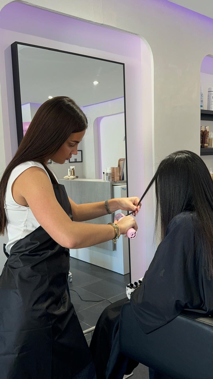 Coiffeuse en train de lisser les cheveux d'une cliente